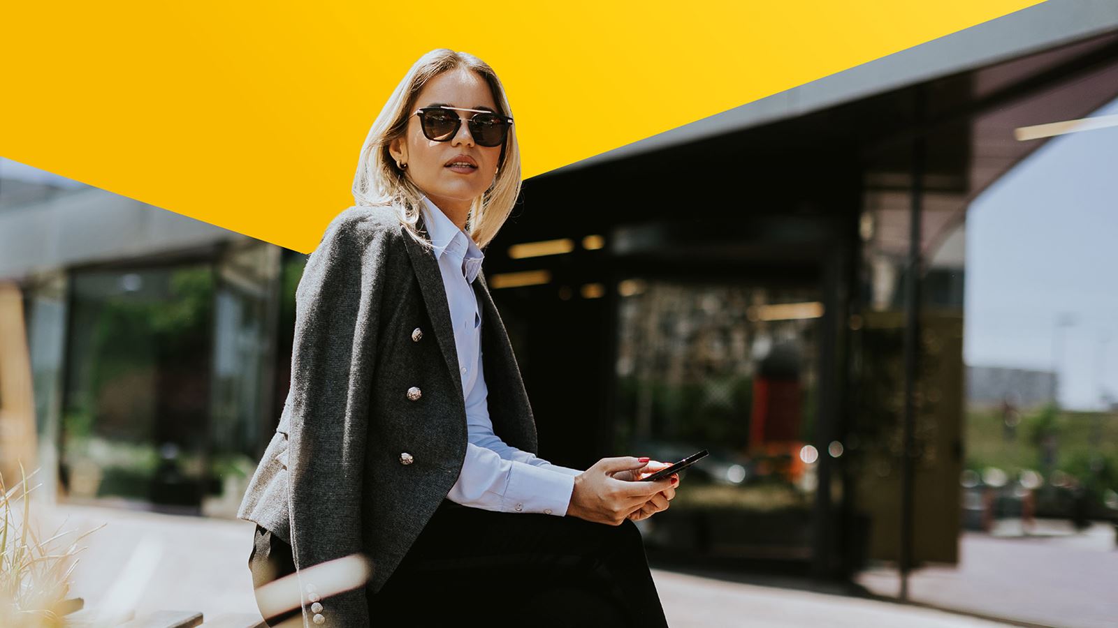 Una donna seduta al sole indossa degli occhiali da sole (con un elemento di design giallo sopra)