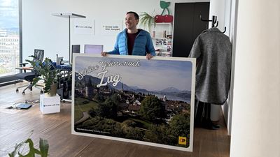 Joel de Buren, Leiter Marketing und Nachhaltigkeitsverantwortlicher von Zug Tourismus mit seiner XXL-Postkarte im Büro