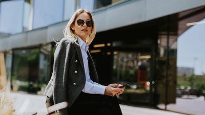 Una donna seduta al sole indossa degli occhiali da sole