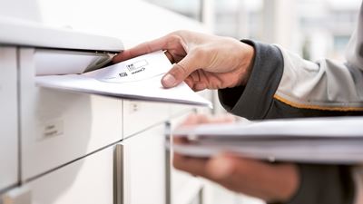 Postbote beim Briefeinwurf in Briefkasten